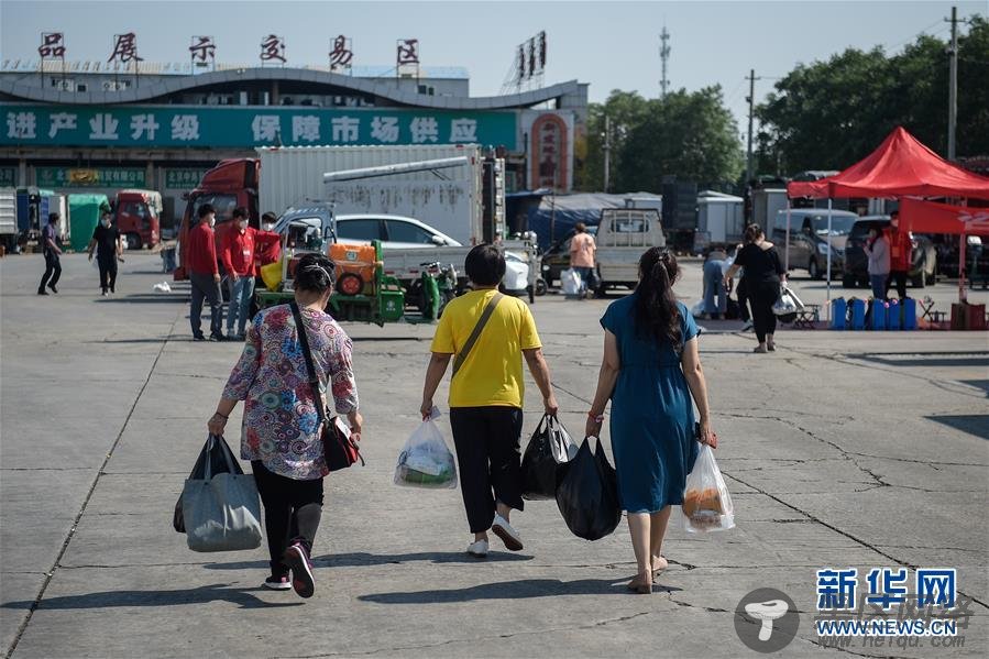 7月7日，在北京新发地市场，解除隔离人员手拎生活用品，前往市场停车区取车。新华社记者 彭子洋 摄